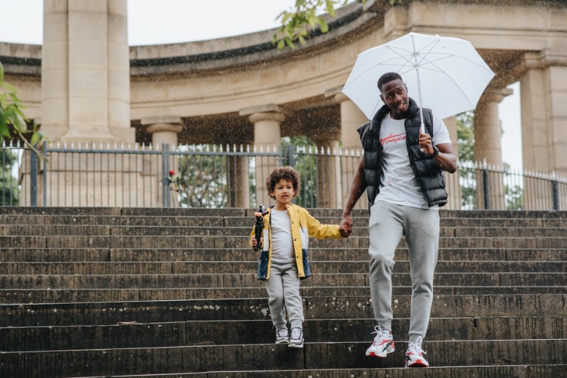 Father holding his sons' hands and an umbrella